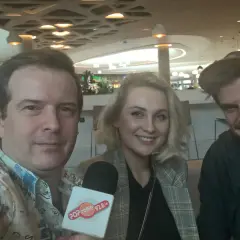 Trzy osoby pozujące do zdjęcia z mikrofonem Popradio.