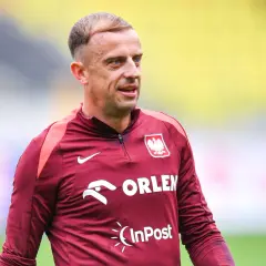 Piłkarz Kamil Grosicki w bordowej koszulce reprezentacji Polski z herbem i logo Orlen.