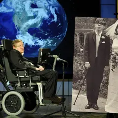 Stephen Hawking na wózku inwalidzkim obok zdjęcia ślubnego z żoną.