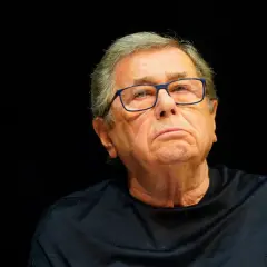 Portret Janusza Gajosa w okularach na czarnym tle.