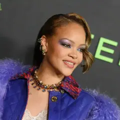 Rihanna w fioletowym futrze i biżuterii, z makijażem oczu.