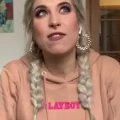Agnieszka Grzelak w różowej bluzie z napisem "LAYBOY", z warkoczami i dużymi kolczykami.