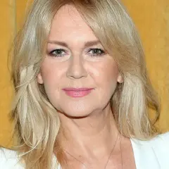 Portret Grażyny Torbickiej z blond włosami na tle żółtej zasłony.
