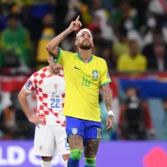Neymar w żółtej koszulce Brazylii z podniesionym palcem, na tle stadionu.
