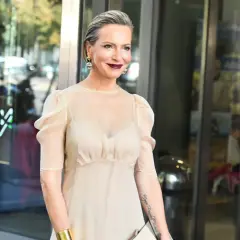 Hanna Śleszyńska w jasnej sukience, z burzą loków i wyrazistym makijażem.