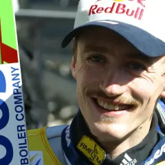 Adam Małysz w czapce Red Bull i z nartami.
