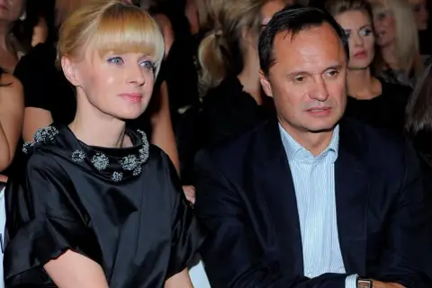Kobieta w czarnej sukni z ozdobnym kołnierzem i mężczyzna w garniturze siedzą obok siebie.