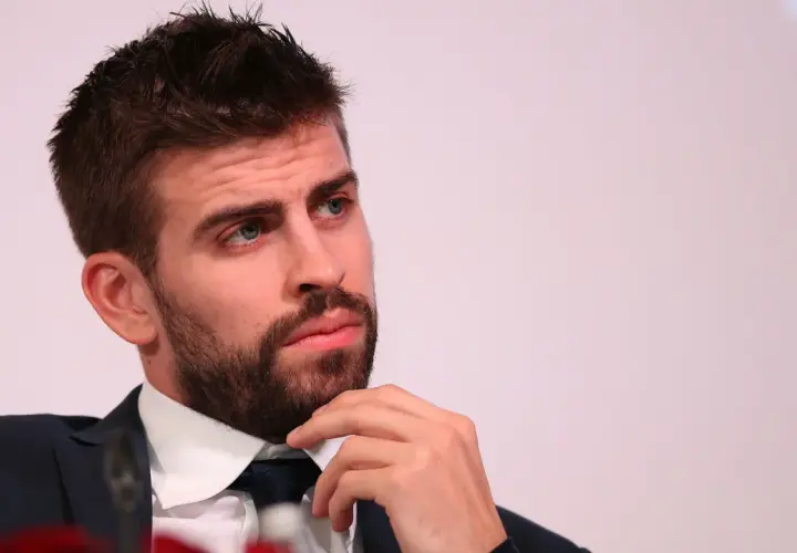 Gerard Piqué w garniturze, z ręką na brodzie, patrzy w bok.