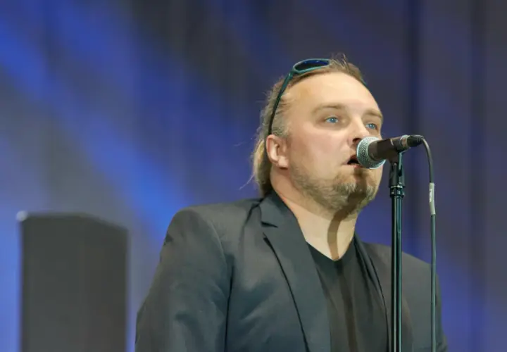 Wojciech Cugowski śpiewający do mikrofonu w czarnej marynarce.