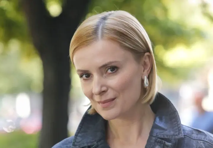Portret Haliny Młynkowej z krótkimi blond włosami, w kurtce, na tle drzew.