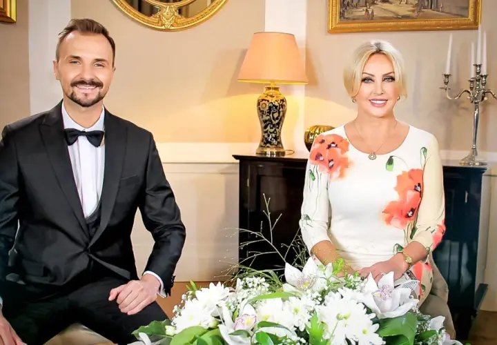 Mężczyzna w garniturze i kobieta w sukience w kwiaty siedzą obok siebie.
