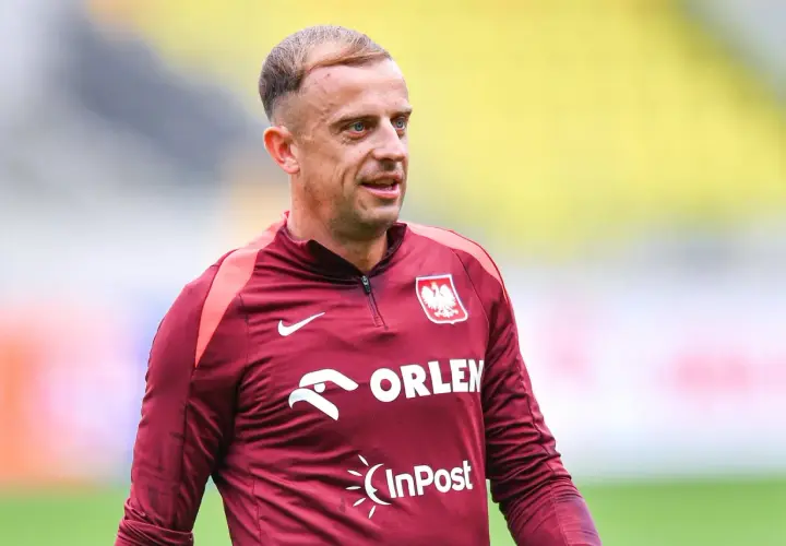 Piłkarz Kamil Grosicki w bordowej koszulce reprezentacji Polski z herbem i logo Orlen.