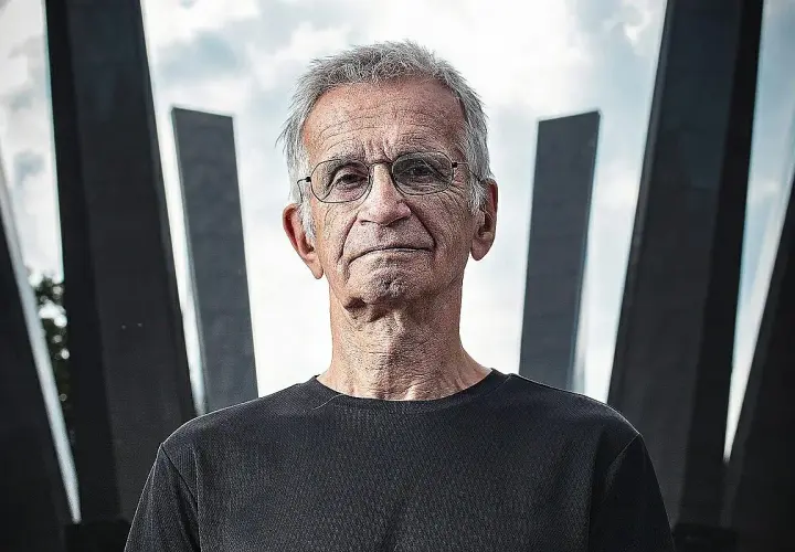 Portret starszego mężczyzny w okularach na tle nowoczesnej architektury.