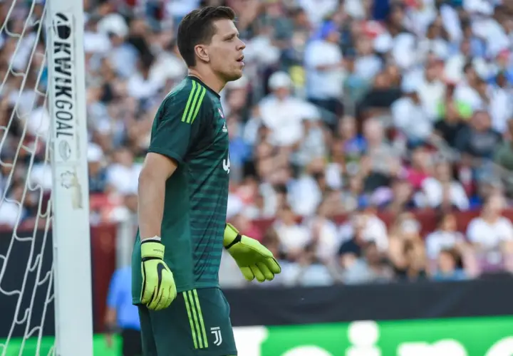 Wojciech Szczęsny w zielonej koszulce bramkarskiej Juventusu stoi przy bramce.