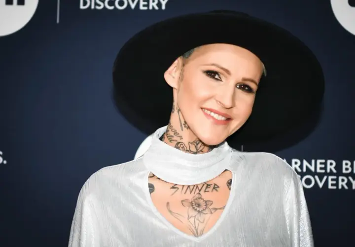 Agnieszka Chylińska w białej bluzce i czarnym kapeluszu, z widocznymi tatuażami na szyi i klatce piersiowej.