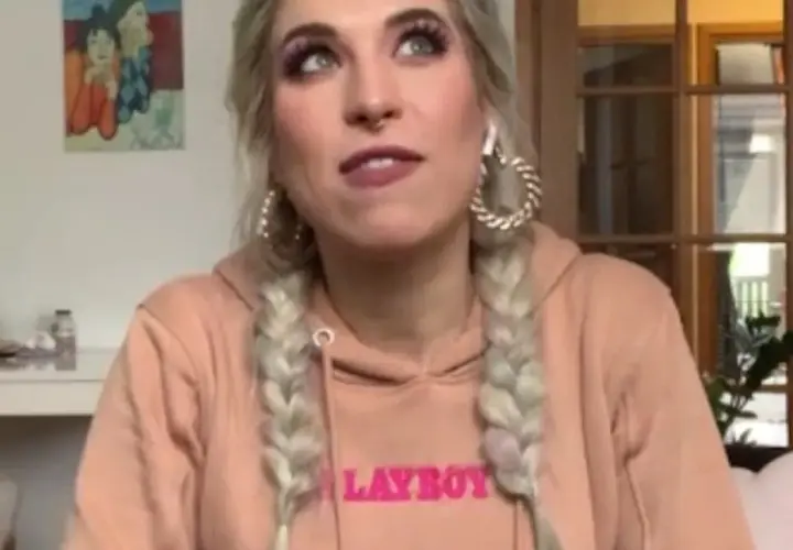 Agnieszka Grzelak w różowej bluzie z napisem "LAYBOY", z warkoczami i dużymi kolczykami.
