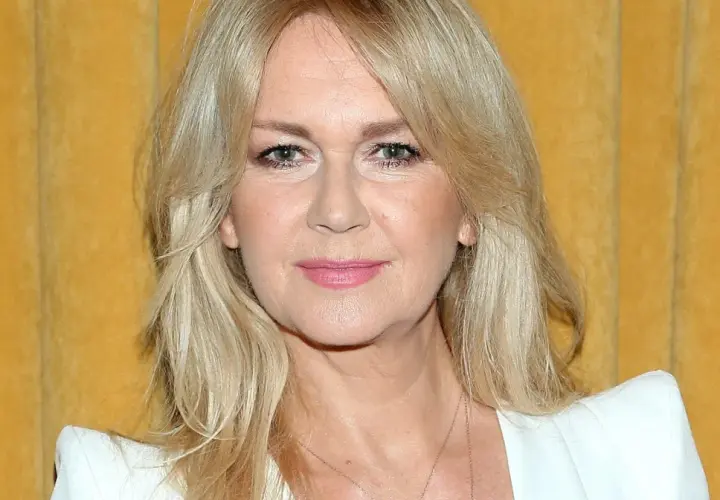Portret Grażyny Torbickiej z blond włosami na tle żółtej zasłony.