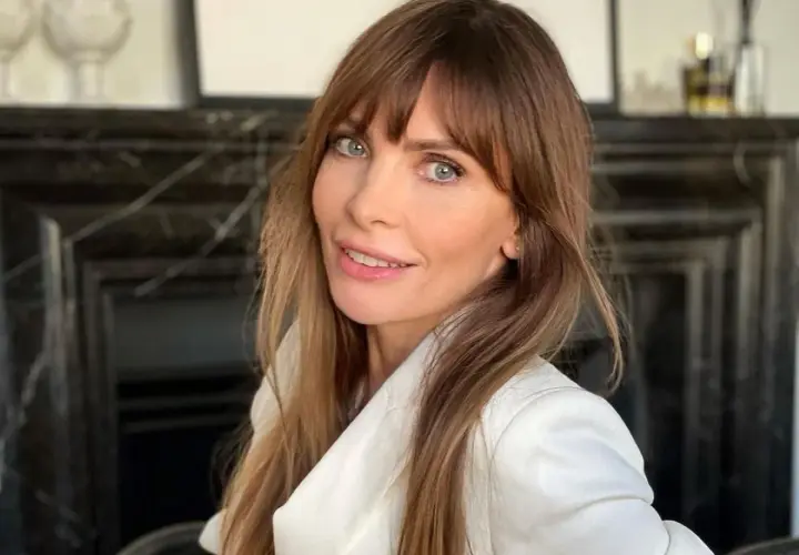 Agnieszka Dygant w białej marynarce, z burzą brązowych włosów i niebieskimi oczami.
