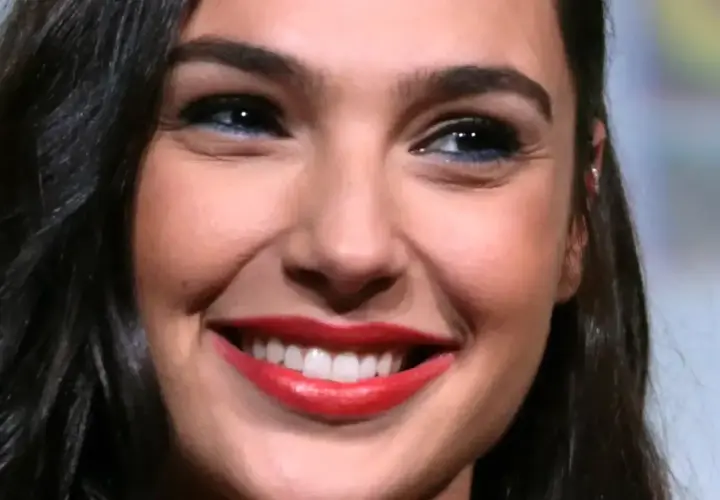 Zbliżenie na twarz Gal Gadot z szerokim uśmiechem i czerwonymi ustami.