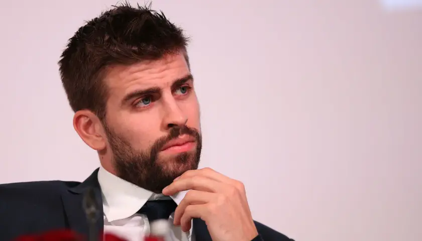 Gerard Piqué w garniturze, z ręką na brodzie, patrzy w bok.