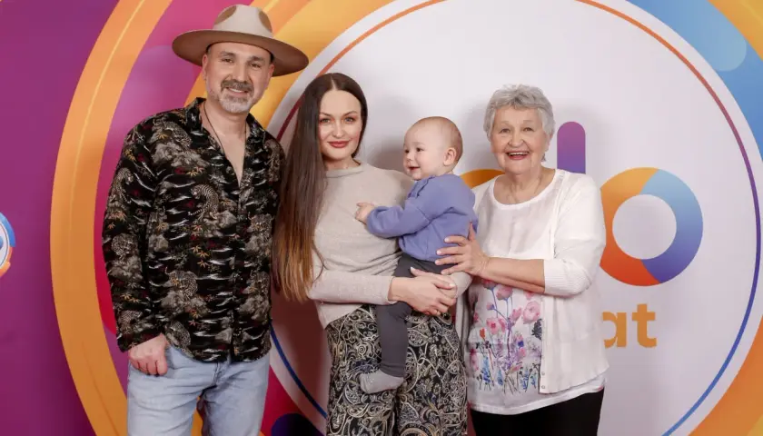 Mateusz Ziółko z rodziną: żoną, synkiem i mamą na tle kolorowego logo.