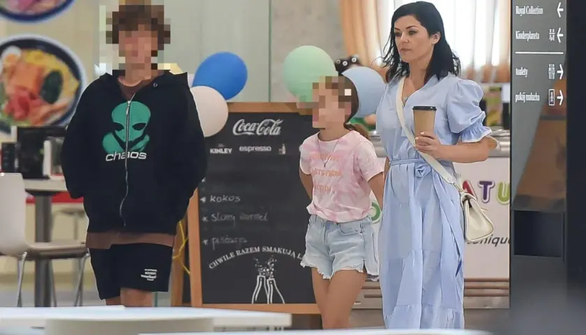 Kobieta w niebieskiej sukience z dwójką dzieci w centrum handlowym.