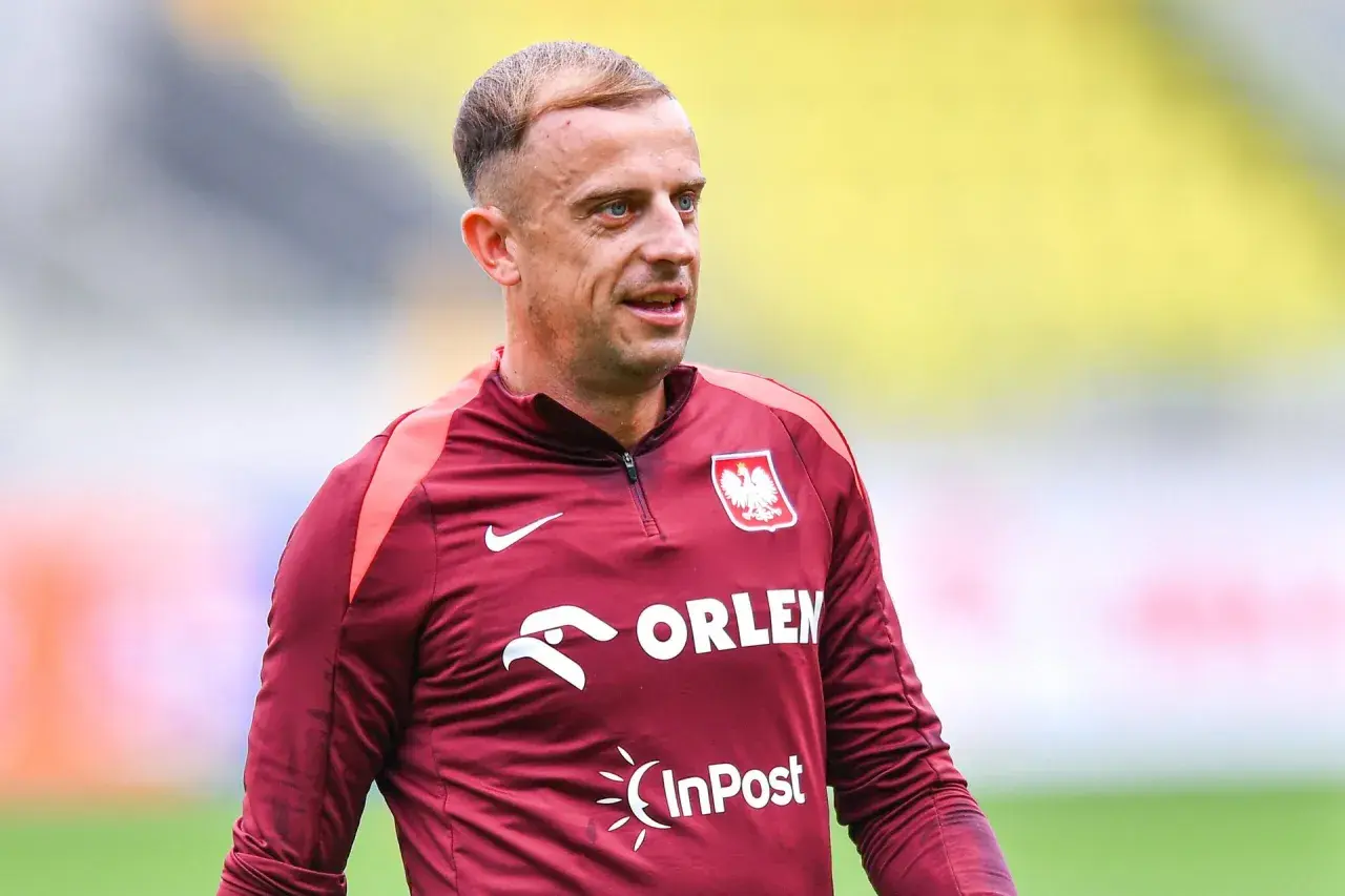 Piłkarz Kamil Grosicki w bordowej koszulce reprezentacji Polski z herbem i logo Orlen.