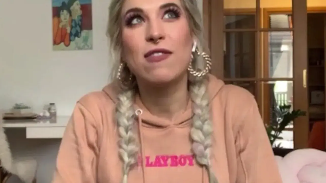 Agnieszka Grzelak w różowej bluzie z napisem "LAYBOY", z warkoczami i dużymi kolczykami.