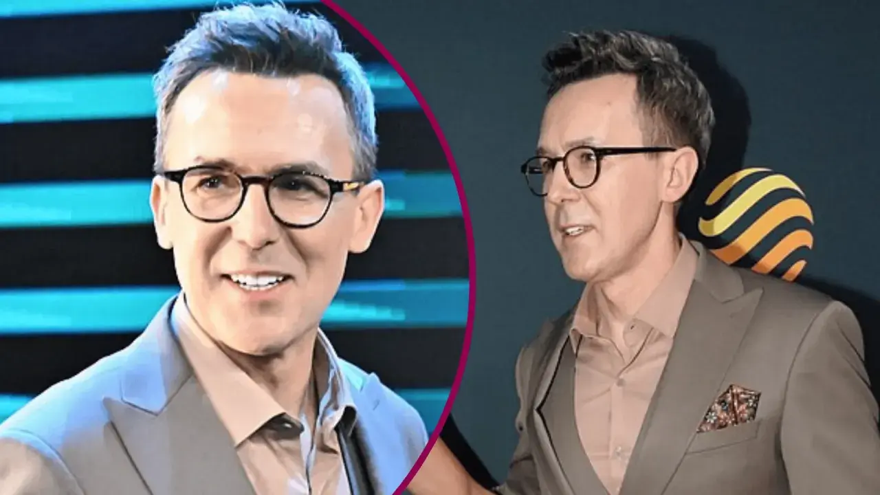 Maciej Kurzajewski w garniturze i okularach, uśmiecha się.