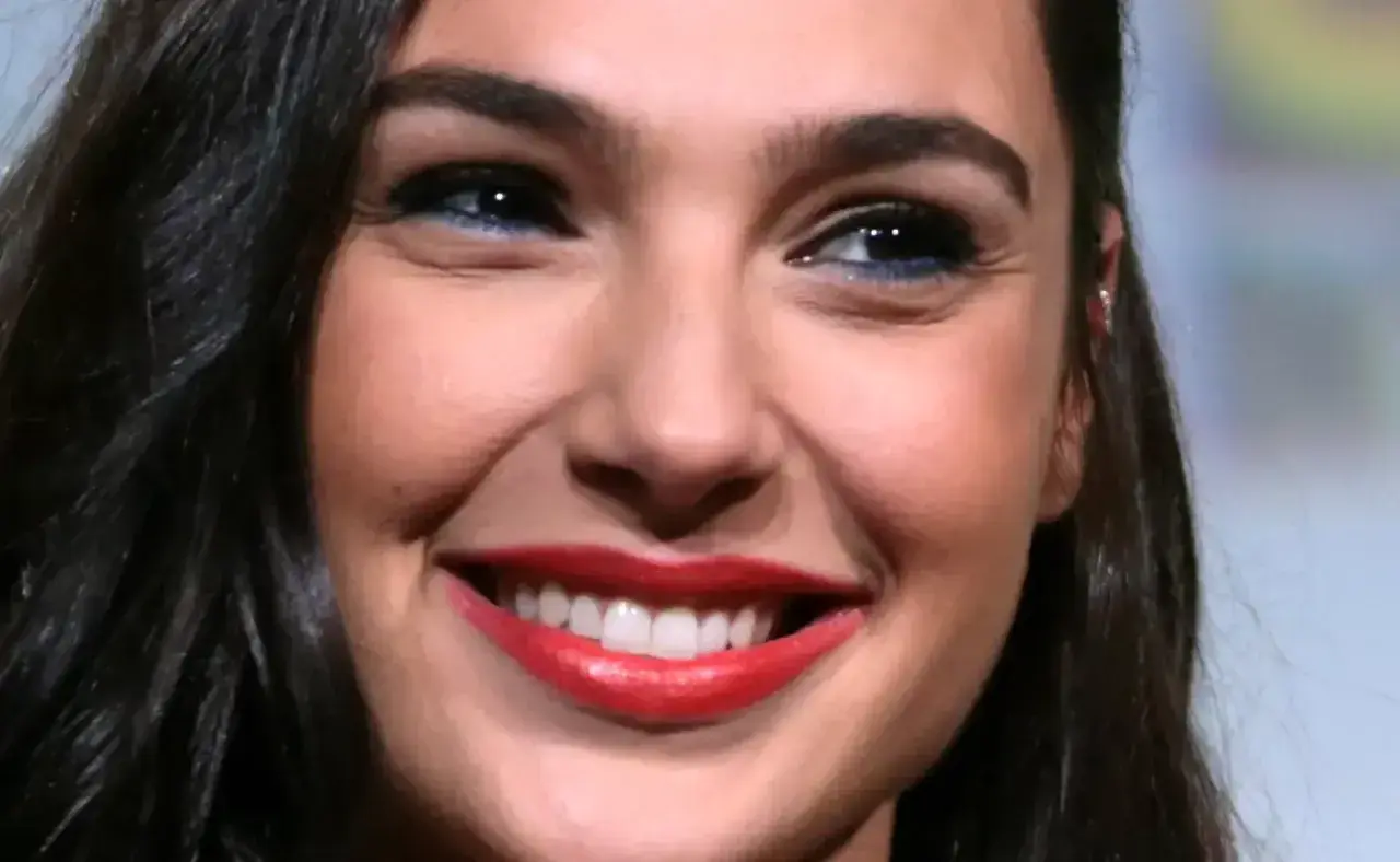 Zbliżenie na twarz Gal Gadot z szerokim uśmiechem i czerwonymi ustami.